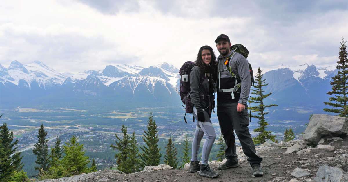 An image of two people at an overlook on a hike through mountains